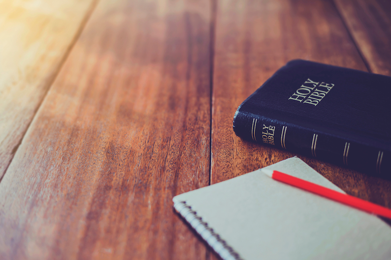 Holy,Bible,With,Note,Book,And,Pencil,On,Wooden,Table